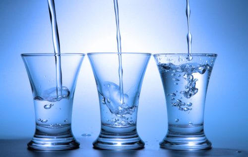 Clear liquid pour into three wineglasses toned in blue color